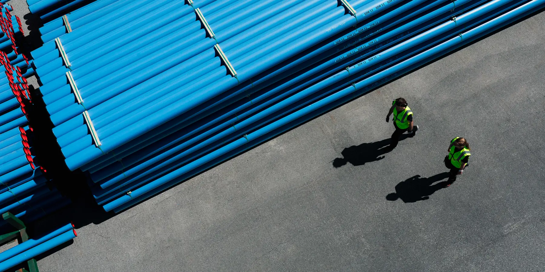 To personer går forbi JAPI-pipe med blå kappe